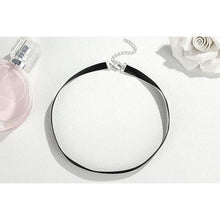 black choker necklace with silver chain attachment on table